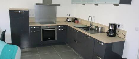 A compact kitchen with a stove, oven, sink, and a coffee maker.
