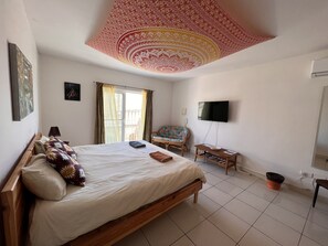 A bedroom with a bed, a chair, a television, and a window with curtains. - All Nations Holiday Home (Ghajnsielem)