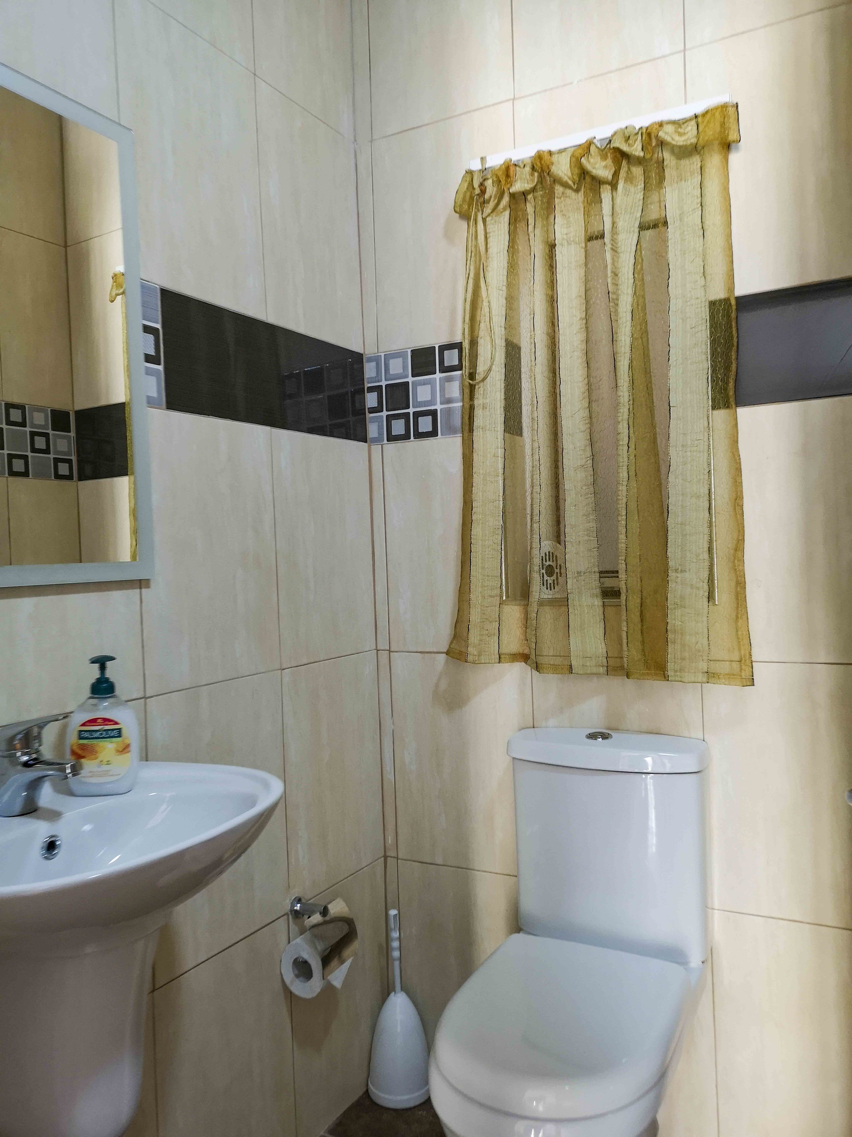 Un baño con lavamanos, inodoro y espejo.