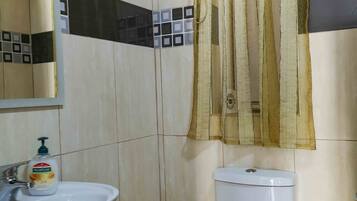 Un baño con lavamanos, inodoro y espejo.