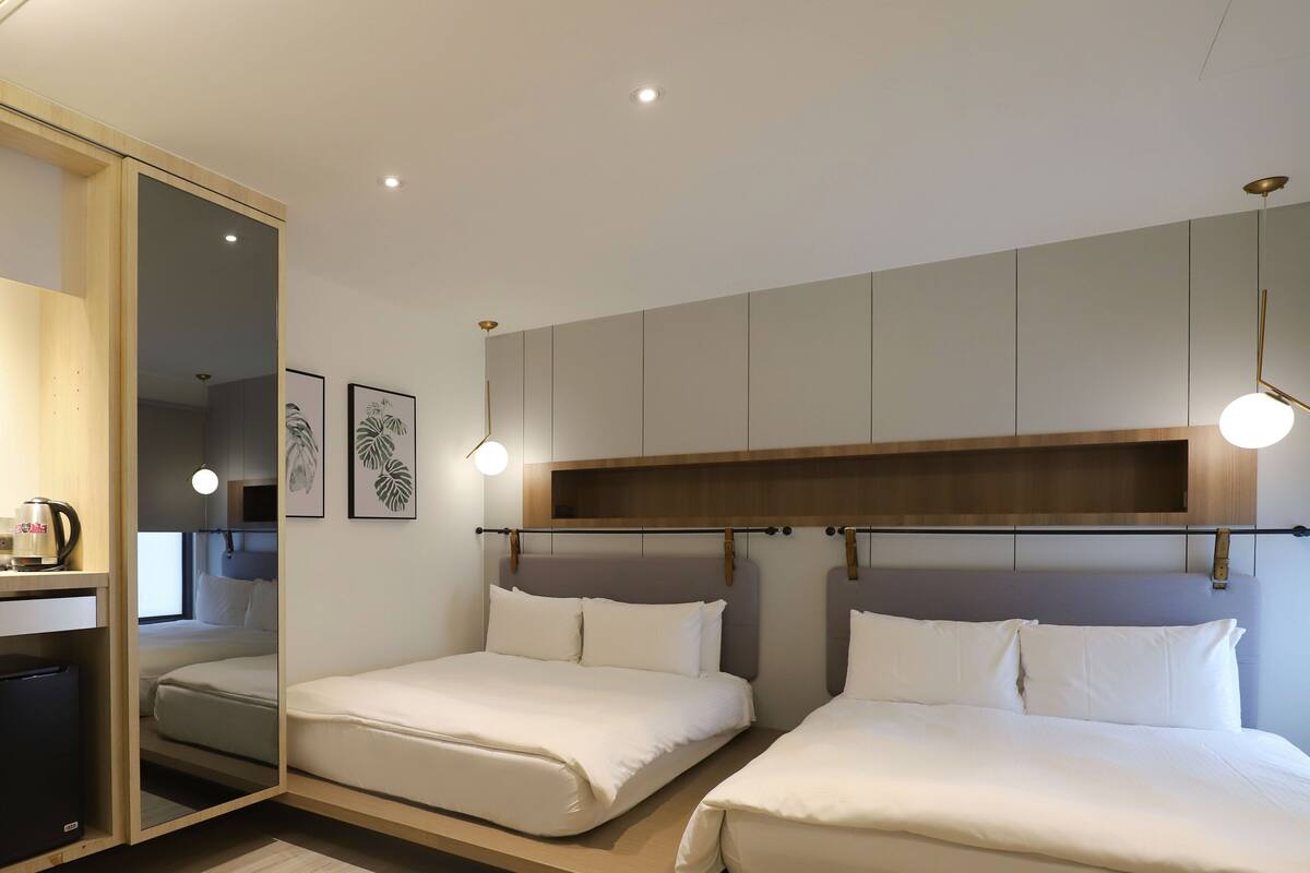 Una habitación de hotel moderna con dos camas, un escritorio integrado y un espejo grande.