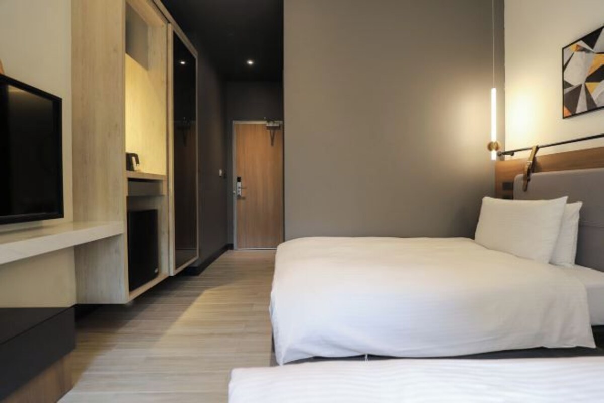 Ett modernt hotellrum med en stor säng, en tv som är monterad på väggen och ett trägolv.