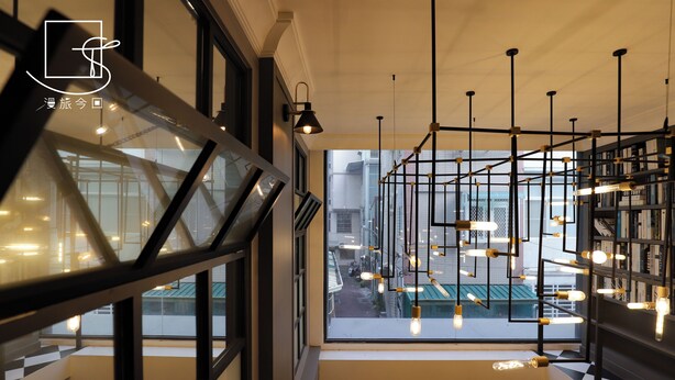 Un intérieur moderne avec un escalier, des luminaires suspendus et une vue sur l’extérieur.