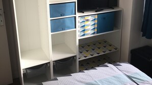 Un dormitorio con cama, armario y televisor.