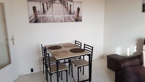 Un comedor con mesa y sillas de madera, un sofá y una gran obra de arte en la pared.