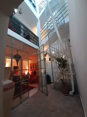 Un intérieur à plusieurs niveaux, doté d’une cloison en verre, d’un escalier et d’un coin salon avec un canapé rouge.
