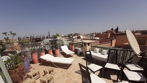 Una terraza en la azotea con sillones de descanso, una mesita y plantas en macetas.