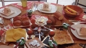 Una mesa de comedor dispuesta con diferentes platos, cubiertos y una botella de agua.