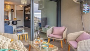 Un salón moderno con muebles de mimbre, una mesa de centro de cristal y vista a la ciudad a través de un ventanal.
