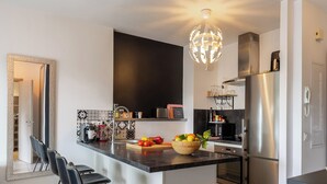 Una cocina moderna con una isla central, electrodomésticos de acero inoxidable y una lámpara decorativa.