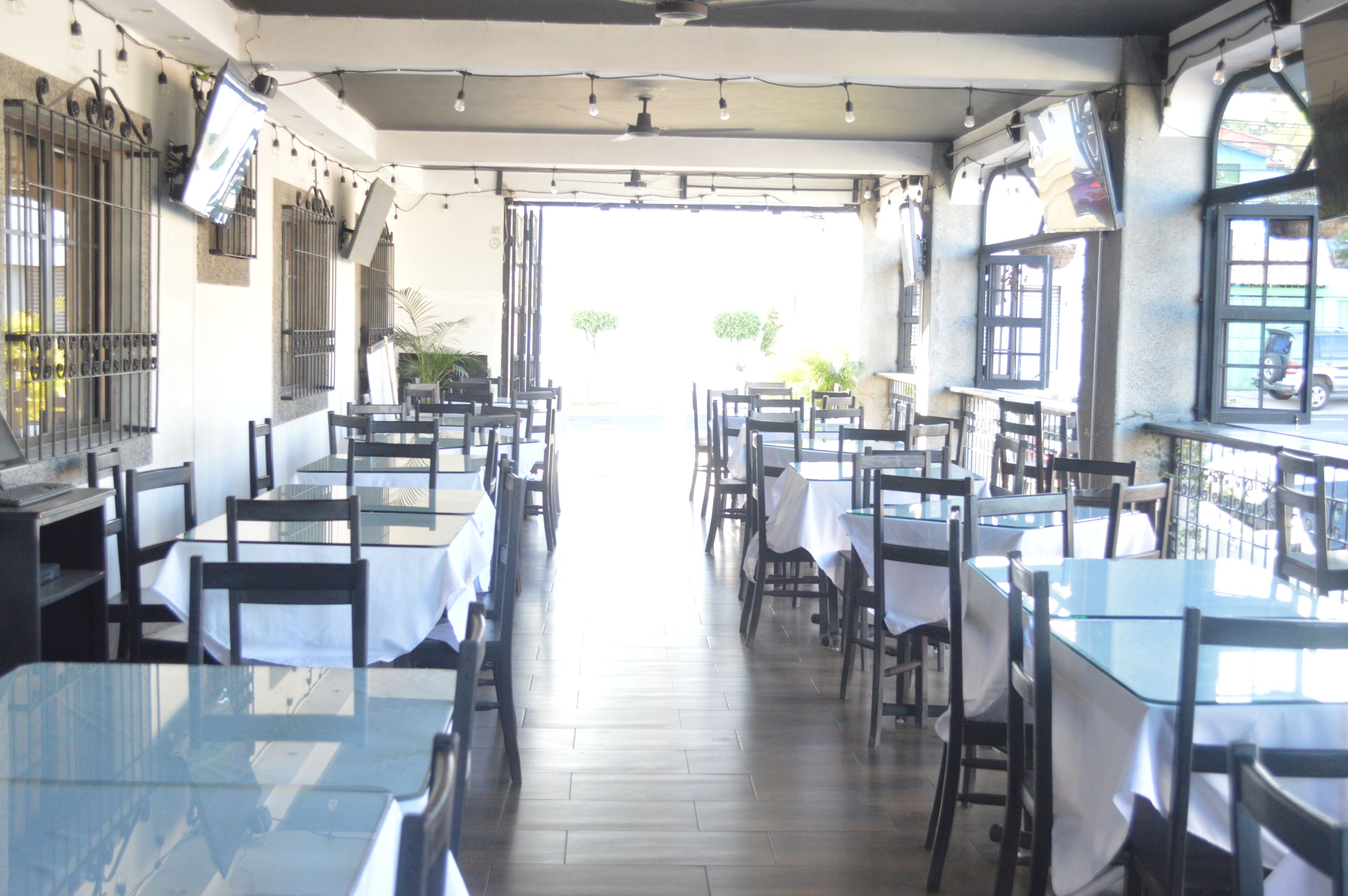 An indoor dining area with tables and chairs, a tiled floor, and a view of the outside.