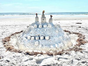 Ett stort sandslott med flera våningar och en rund grund, byggt på en sandstrand.