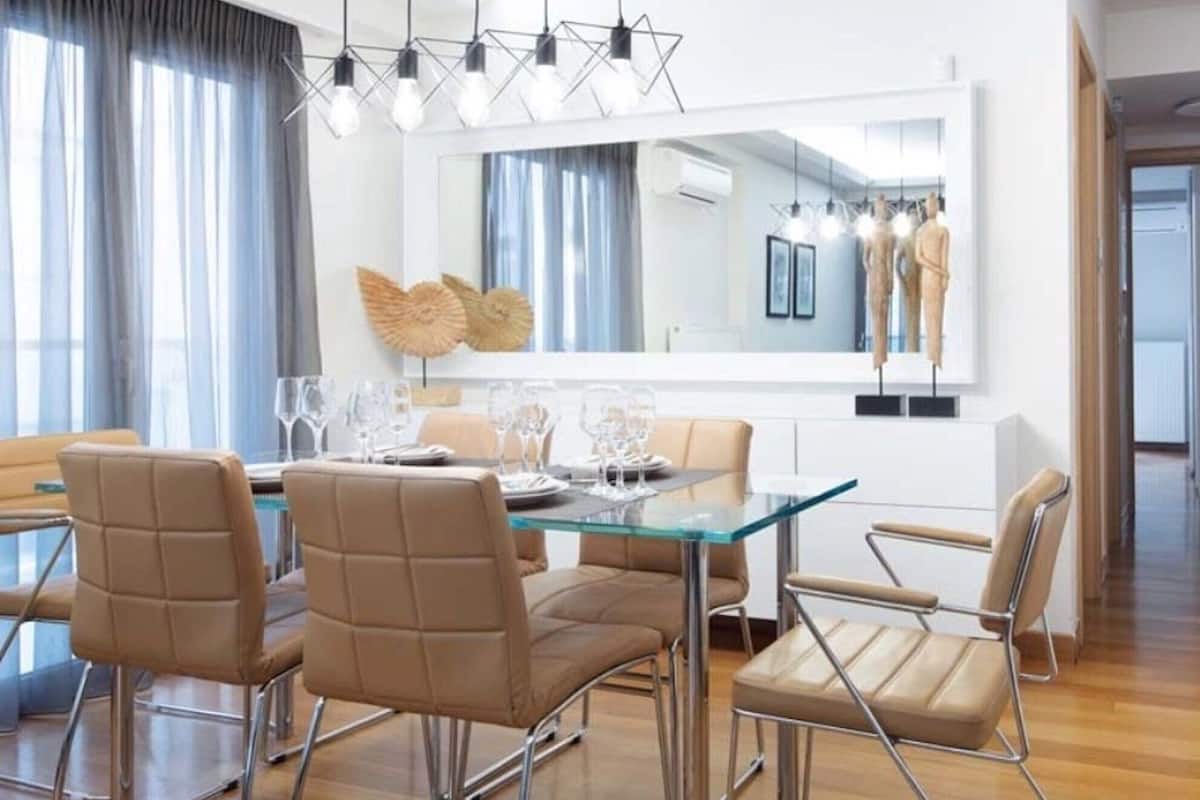 A modern dining area with a glass table, metal chairs, and pendant lighting.