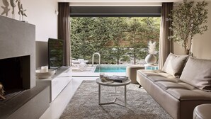 Una sala de estar moderna con chimenea, vista a la piscina y un área de estar acogedora.