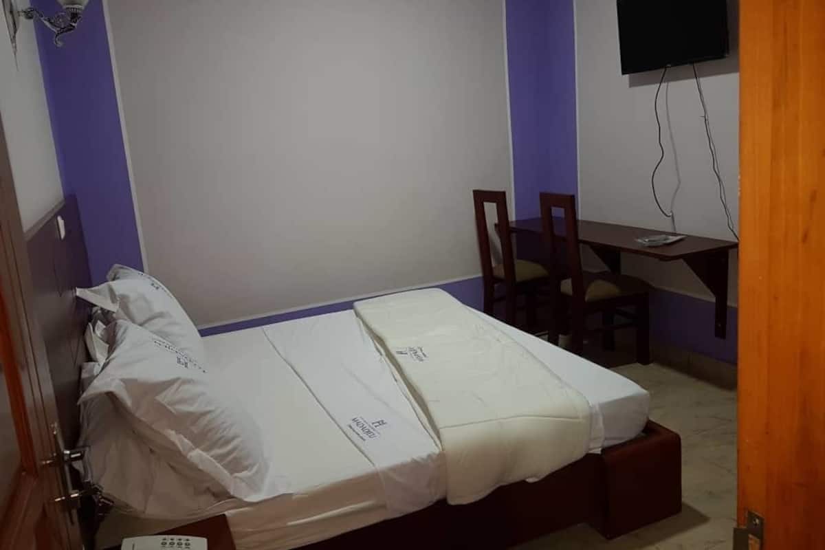 A small room with a bed, a desk, and a television.