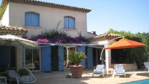 A poolside area with lounge chairs and umbrellas, a building with blue shutters, and a clear blue pool. - VILLA GOLFE DE SAINT TROPEZ (Cogolin)
