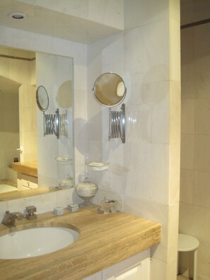 A bathroom with a wooden vanity, a large mirror, and a small sink.