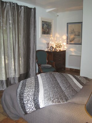A bedroom with a bed, a chair, a dresser, and two framed pictures on the wall.