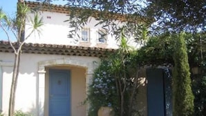 A building with a white facade, a blue door, and a tiled roof. - VILLA GOLFE DE SAINT TROPEZ (Cogolin)