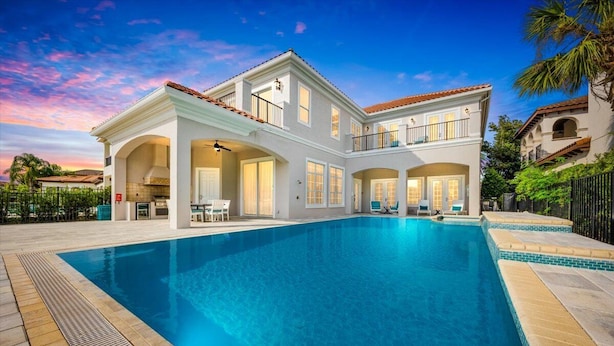 Ein großes, zweistöckiges Haus mit einem Schwimmbad davor.