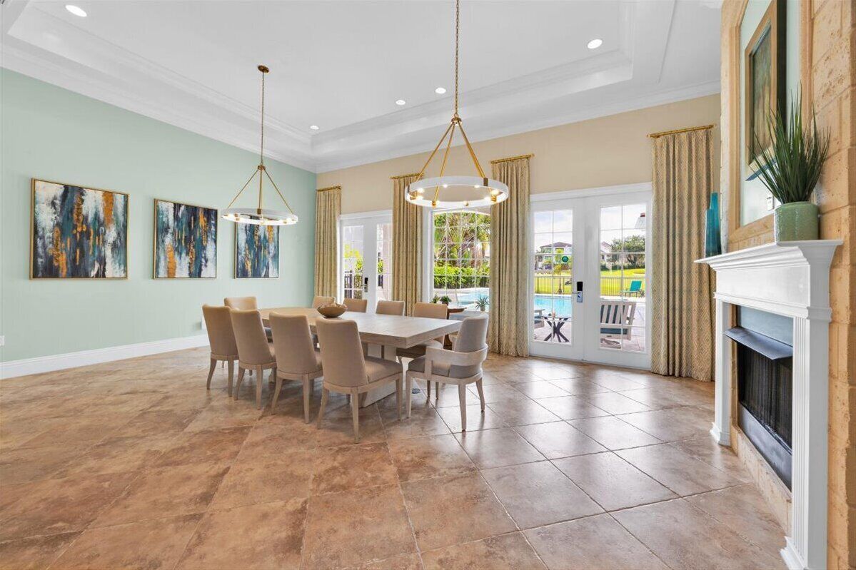 A spacious dining area with a large table and chairs, a fireplace, and artwork on the walls.
