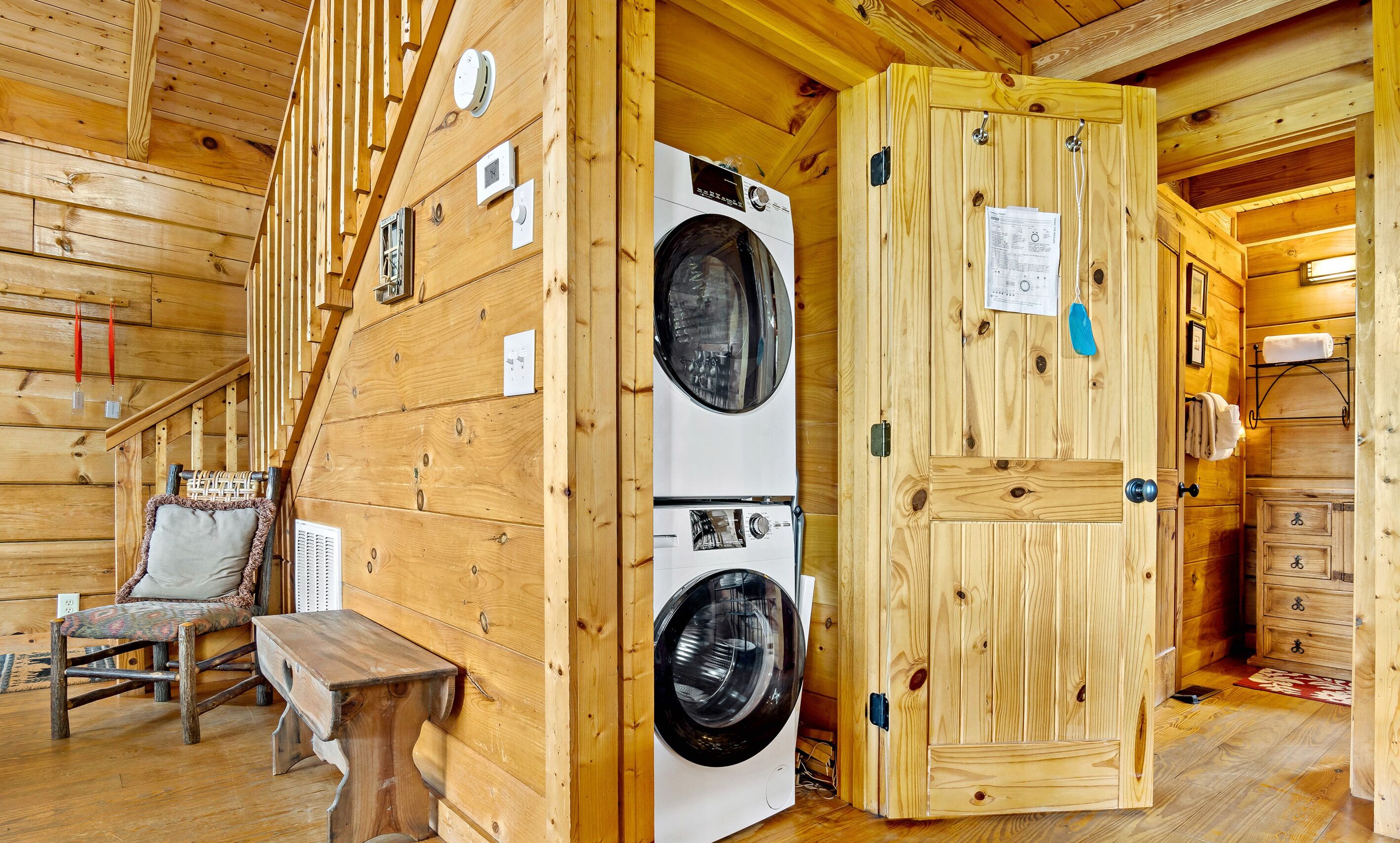 Un intérieur en bois comprenant un lave-linge, un banc et une porte avec un porte-serviettes.