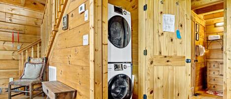 Un intérieur en bois comprenant un lave-linge, un banc et une porte avec un porte-serviettes.