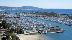 An aerial view of a marina with numerous boats docked, surrounded by hills and a clear sky. - Modern Beach Condo - Luxury Coastal Retreat (Monarch Beach)