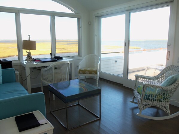 Una habitación con escritorio, dos sillas, un sofá y vistas a la playa.