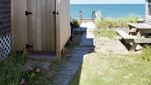 Eine Holzterrasse führt zu einem Haus mit Meerblick.