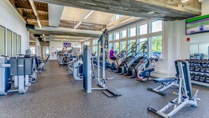 Uma academia com diversos equipamentos de exercícios, esteiras e halteres.