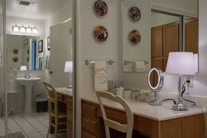 A bathroom with a sink, mirror, vanity, and decorative plates on the wall. -  Immaculate Cottage Retreat with Saltwater Pool (Phoenix)