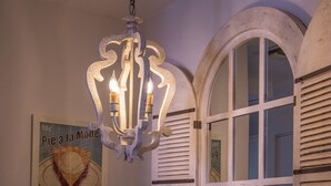 Un coin repas avec une table en bois, des chaises, un vase de fleurs, un lustre et une affiche accrochée au mur.