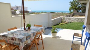 A patio with a table and chairs, a potted plant, and a view of the sea. - GOLDEN SAND - Punta Braccetto  (Punta Braccetto)