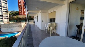 En balkon med pool, hvide stole og en ventilator.