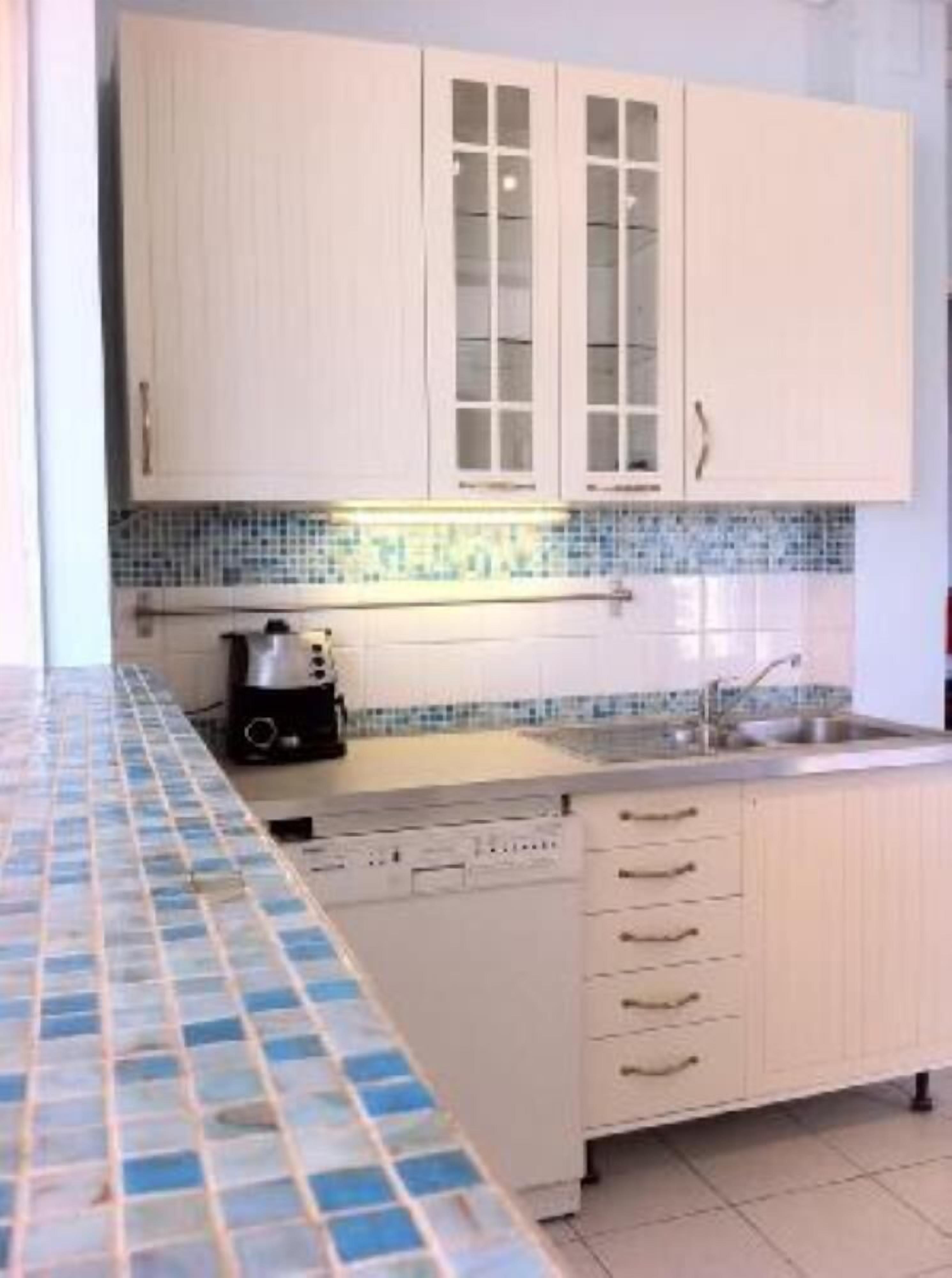 Een keuken met witte kastjes, een betegelde achterwand en een vaatwasser.