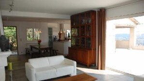 A spacious living area with a white sofa, wooden coffee table, and a glass cabinet. - Contemporary Sea-View Villa with Infinity Pool – Near Saint-Paul de Vence (La Colle-sur-Loup)