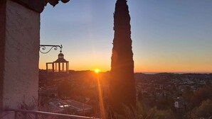 A sunset view from a balcony overlooking a town with a prominent tower and a gazebo. - Contemporary Sea-View Villa with Infinity Pool – Near Saint-Paul de Vence (La Colle-sur-Loup)