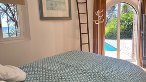 A bedroom with a bed, a ladder, a framed picture, and a view of the outdoors. - Contemporary Sea-View Villa with Infinity Pool – Near Saint-Paul de Vence (La Colle-sur-Loup)