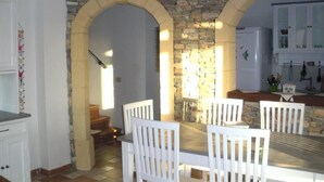 A dining area with a stone wall, white chairs, and a table.