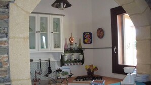 A kitchen with stone walls, a gas stove, a sink, and a window with a view.