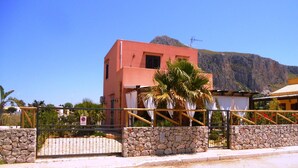 A pink building with a stone wall and a metal gate in front.