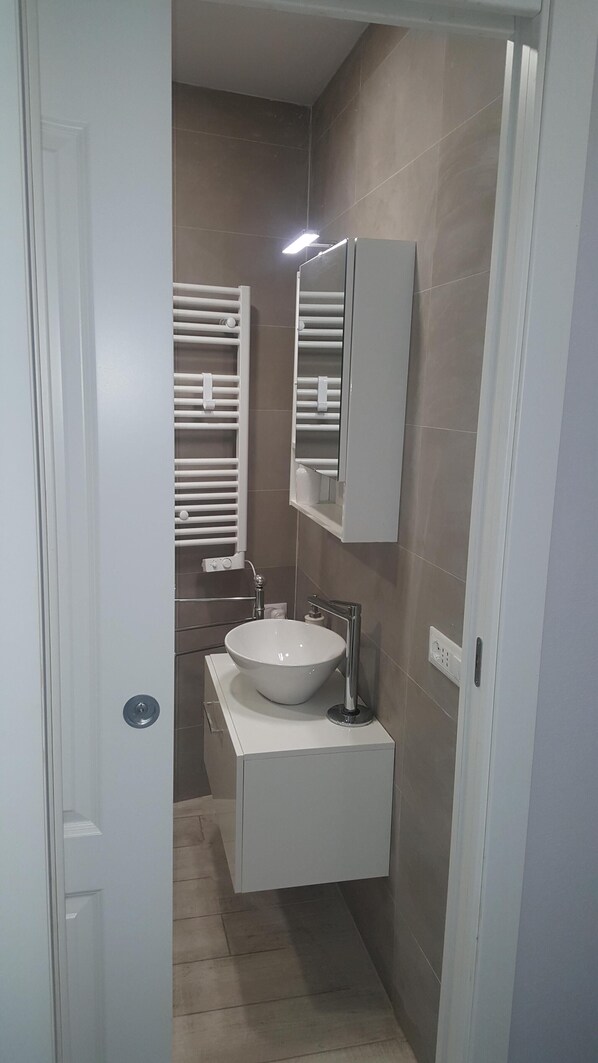 A modern bathroom with a white sink, a mirror, and a towel rack.