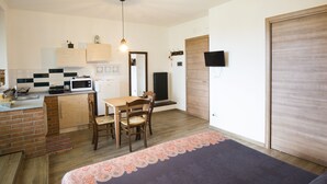 Une cuisine compacte avec un coin repas, un téléviseur fixé au mur et une porte en bois.