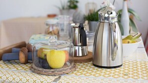 Un comptoir de cuisine avec une machine à café, un bocal en verre rempli de pommes et un panier en osier.