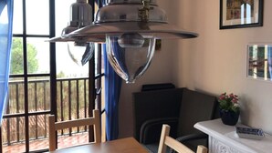 Una zona de menjador amb una taula de fusta, cadires i una finestra gran amb cortines blaves.