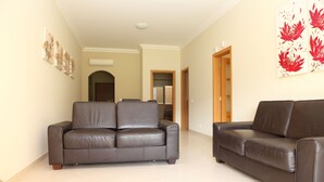 A spacious living room with two dark brown leather sofas, a tiled floor, and a door leading to another room. - Fully licensed prestigious Algarve apartment for rental in Vilamoura (Quarteira, Vilamoura)