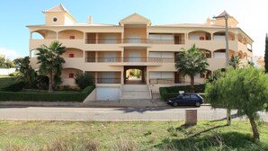 A multi-story building with a central entrance, balconies, and a car parked in front. - Fully licensed prestigious Algarve apartment for rental in Vilamoura (Quarteira, Vilamoura)