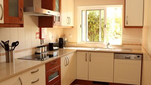 A modern kitchen with white cabinets, a built-in oven, and a window providing natural light. - Fully licensed prestigious Algarve apartment for rental in Vilamoura (Quarteira, Vilamoura)