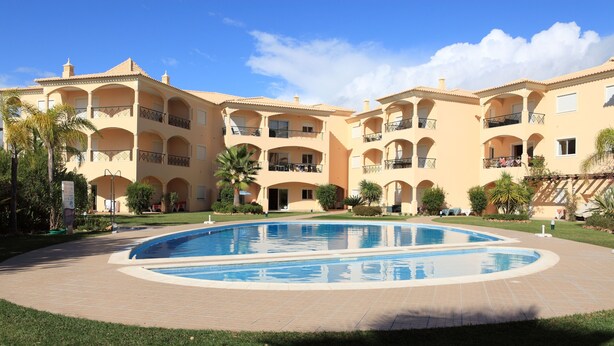 A multi-story hotel with a central swimming pool, surrounded by well-maintained lawns and palm trees. - Fully licensed prestigious Algarve apartment for rental in Vilamoura (Quarteira, Vilamoura)